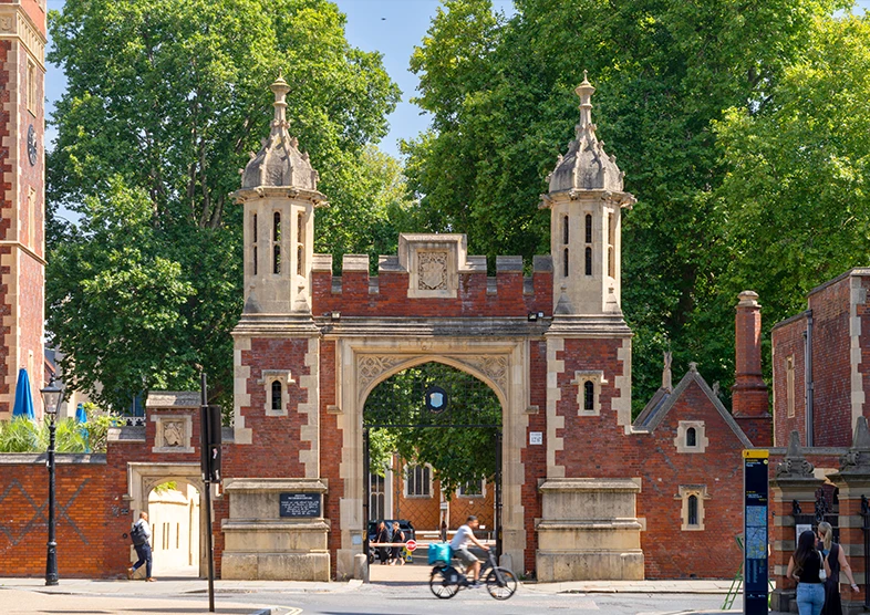 The main entrance gate of Lincoln’s Inn in
London, known as the Gatehouse, featuring a
historic red-brick archway with stone towers and
people passing by on a sunny day.