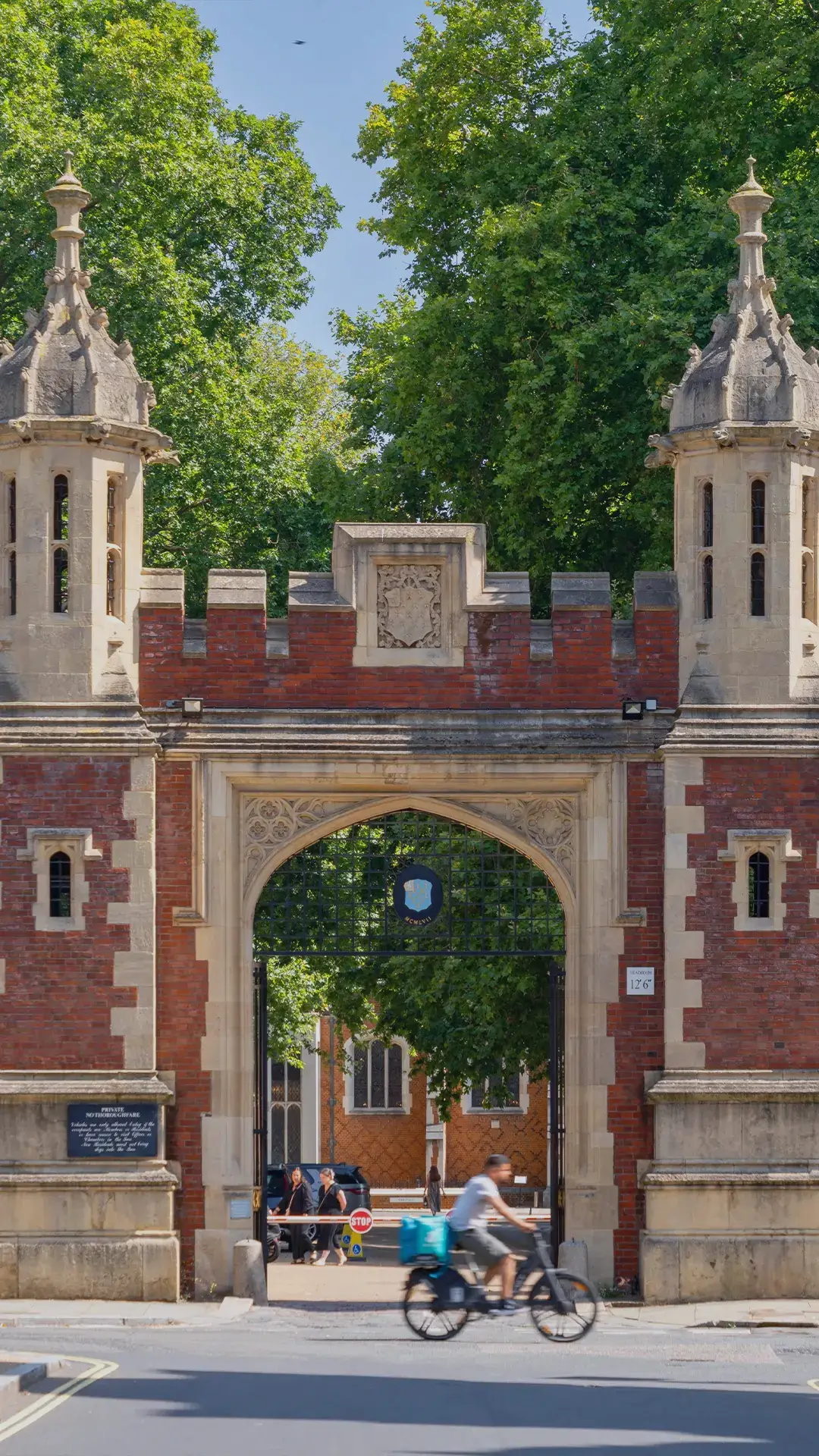 The main entrance gate of Lincoln’s Inn in
London, known as the Gatehouse, featuring a
historic red-brick archway with stone towers and
people passing by on a sunny day.